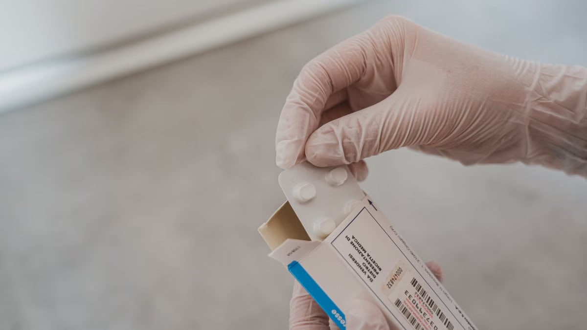 Close-up of hands in gloves handling medication blister pack, ensuring safety and hygiene in healthcare.